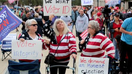 Demonstrators hold up signs advocating for voter fairness.