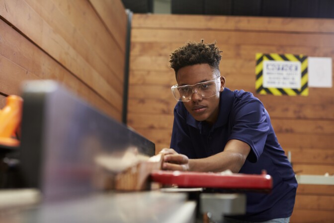 A carpenter uses a plane in a woodworking woodshop.