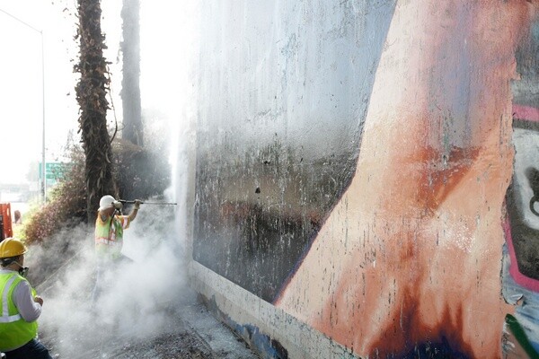 Graffiti being cleaned away from Jim Morphesis Monument I Photo: Gil Ortiz Photos