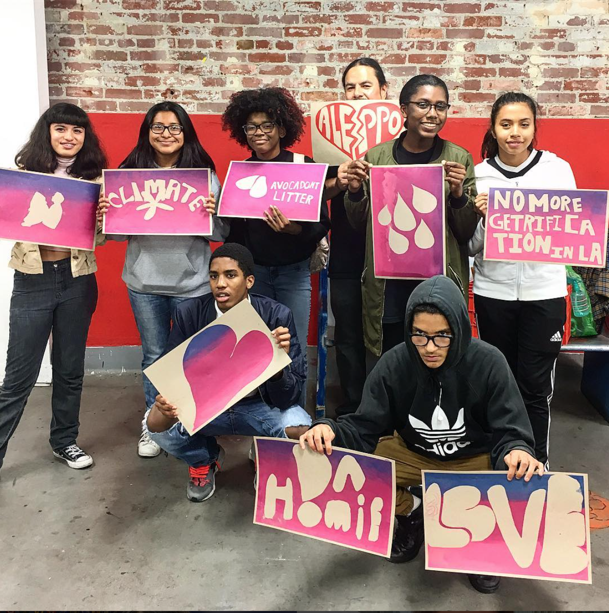 Youth hold up their screen printed posters with Dewey Tafoya.