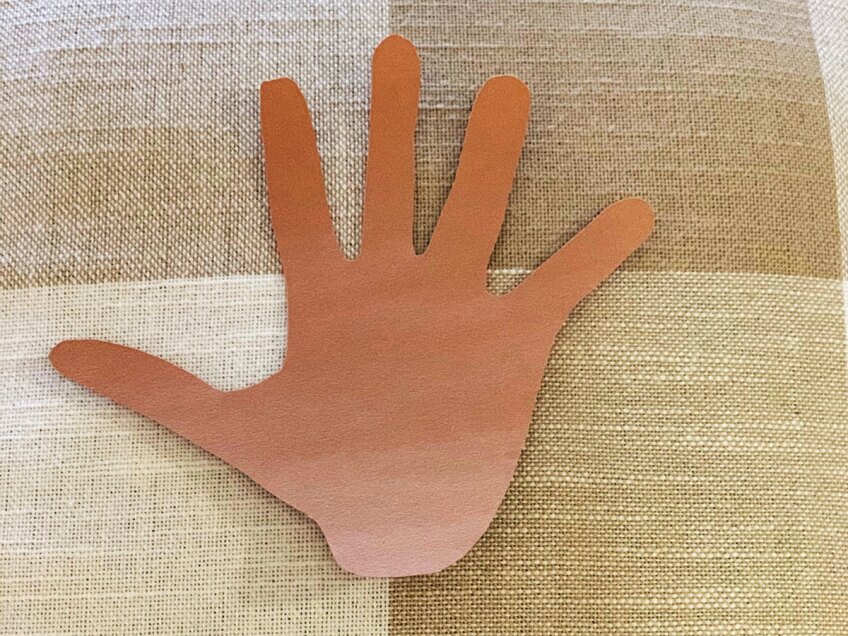 Children's hand cut out of brown construction paper to make a mindfulness turkey craft