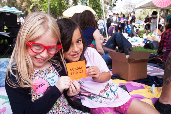 Kids giving away free stickers from Sunday Service at Dyke Day | Photo: Maya Santos