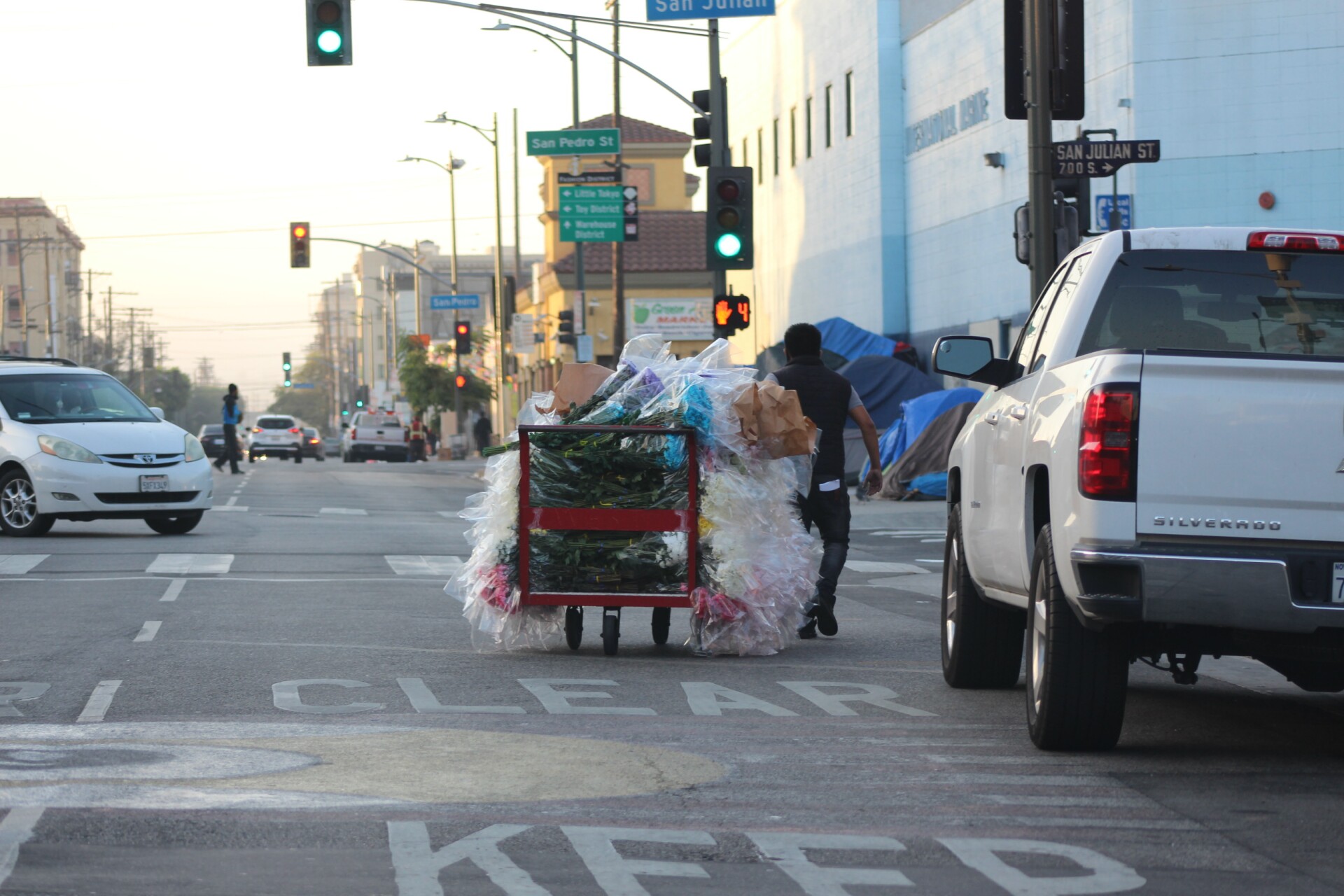 Man with flowers on cart pulls them through San Julian Intersection | Karen Foshay