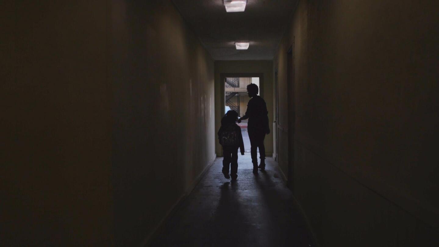A child and a woman walk through a dark hallway.