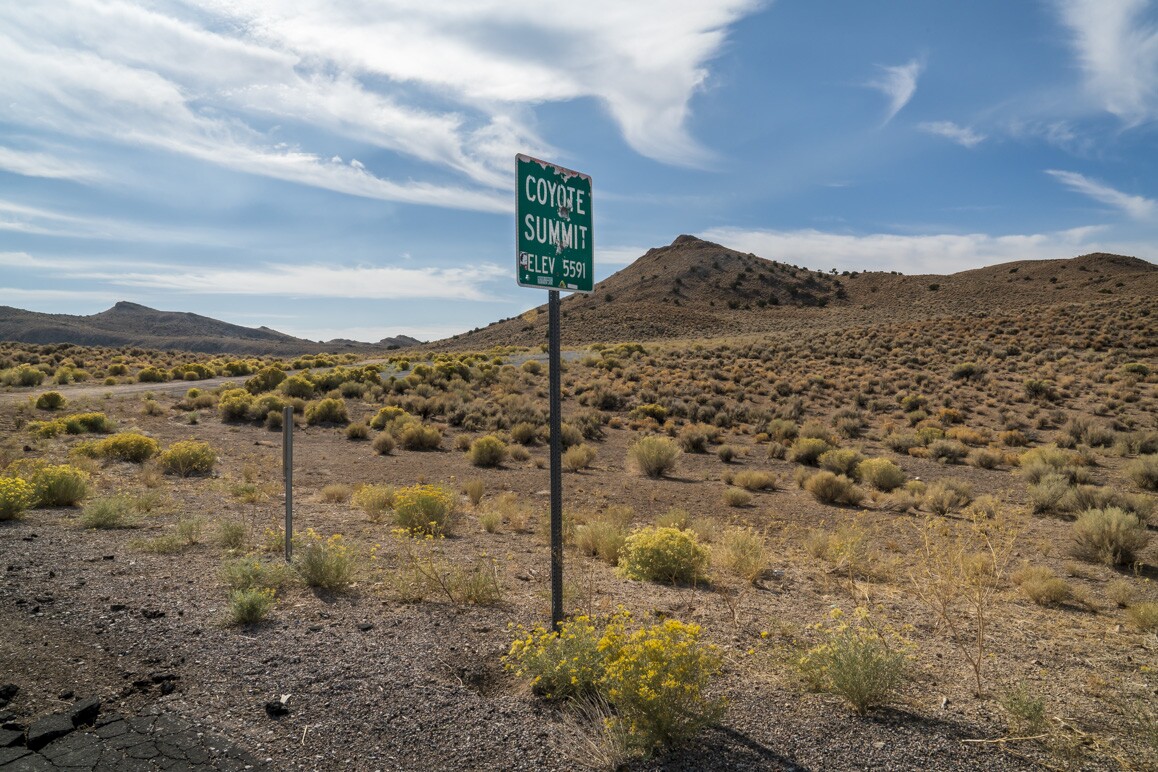 A desert landscape with a sign that says Coyote Summit.