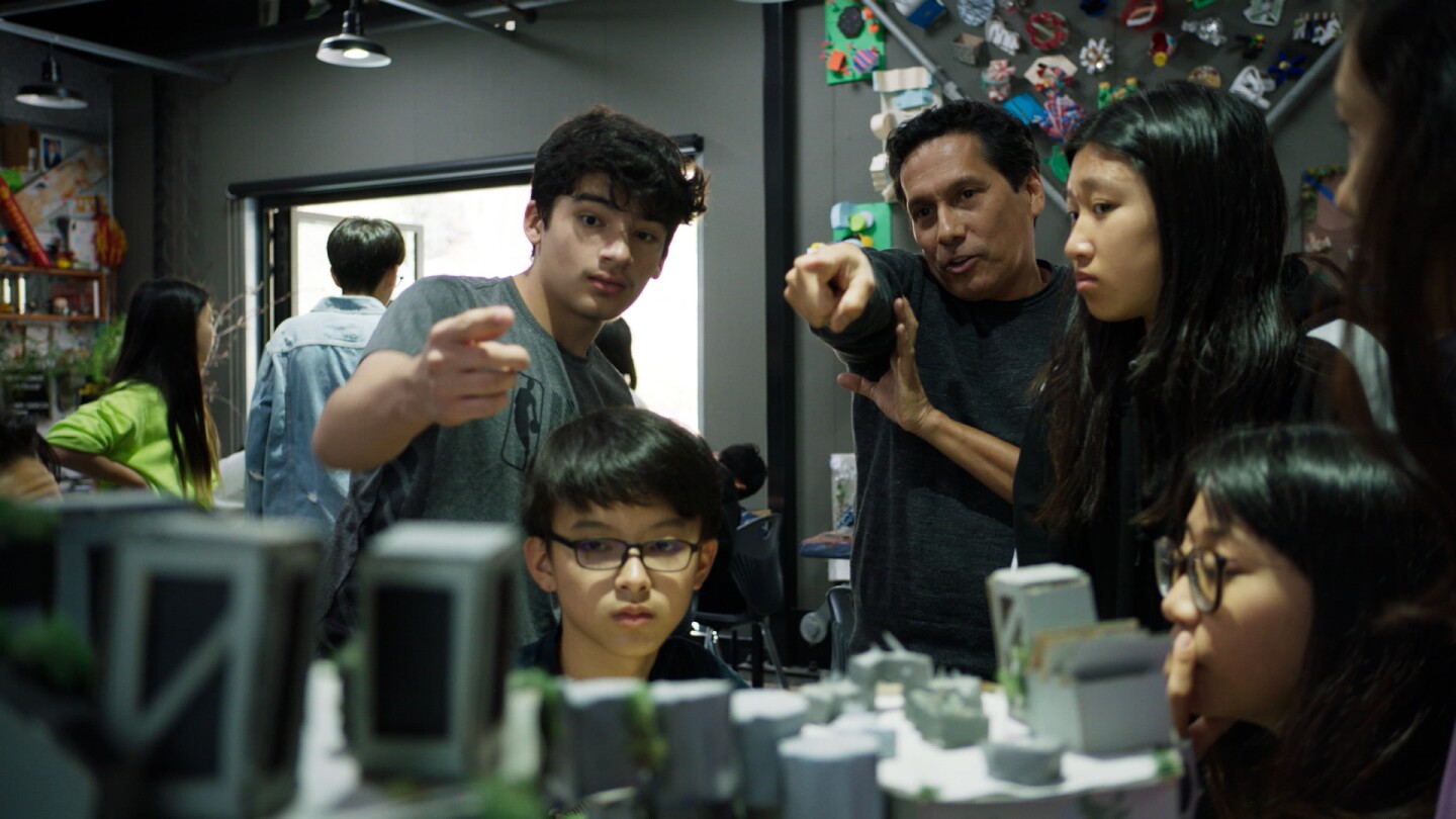 A teacher and his class talk about a model they're building inside a creative classroom.