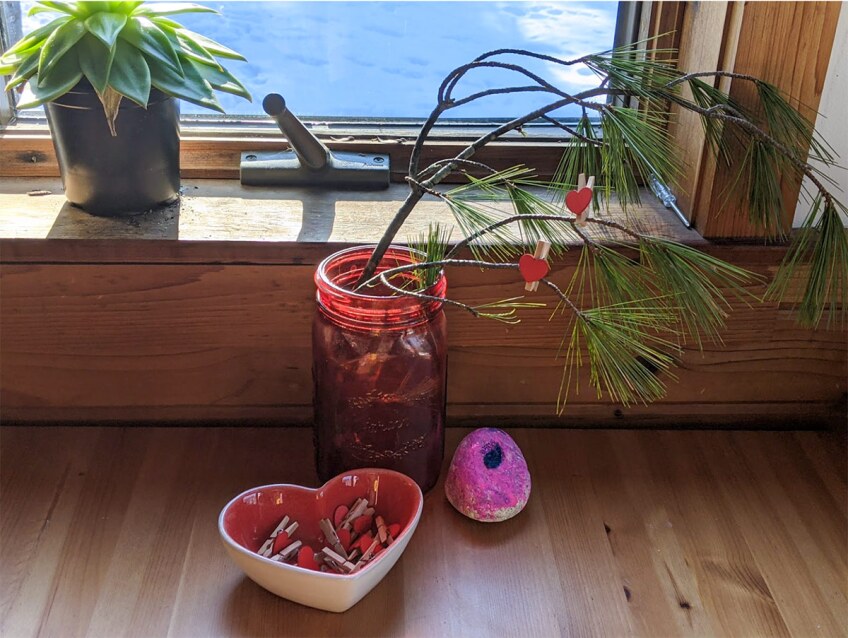 a branch in a jar is filled with clothespins with hearts on them
