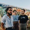 The members of Thee Sacred Soul stand together in front of a mural.