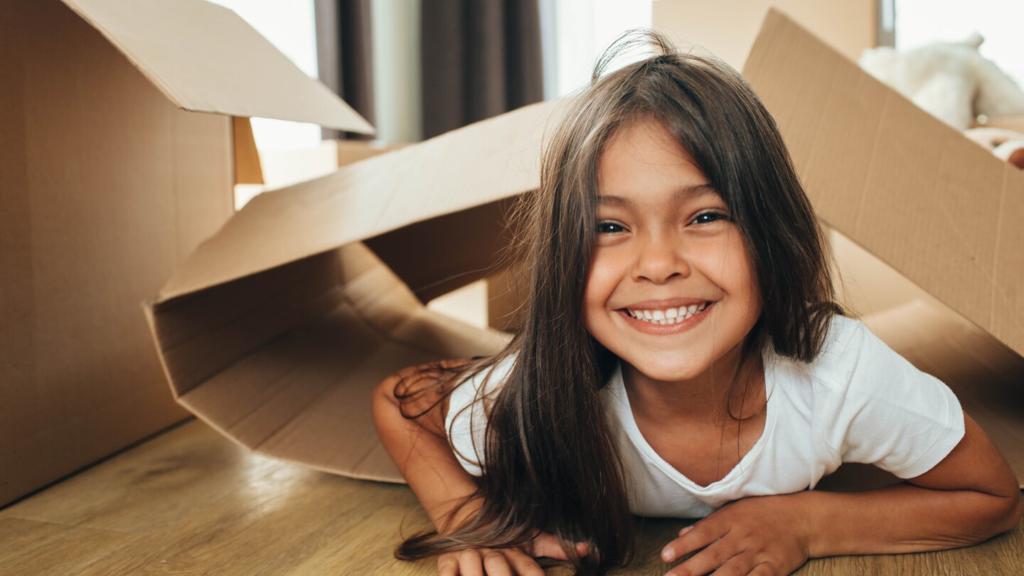 little girl playing with Cardboard Box, into her new house.
