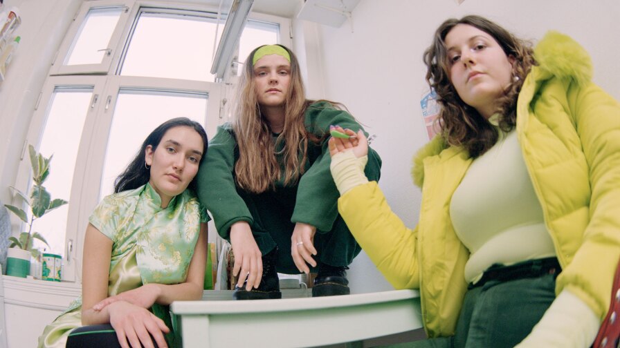 Still from Sassy's "Are You Leaving": 3 Women in a white room, seen from a fish-eye perspective