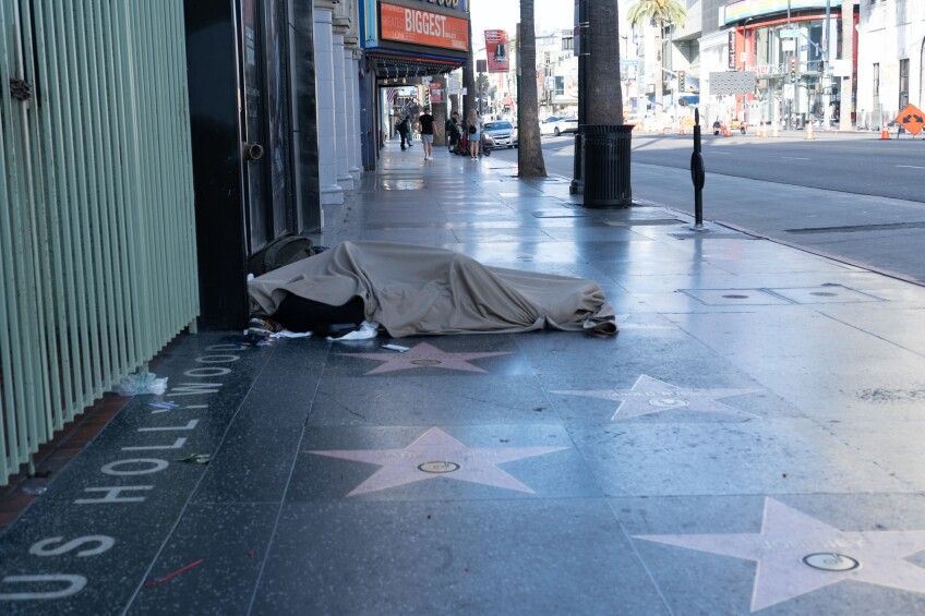 A homeless man sleeps on the sidewalk of the Hollywood Walk of Fame on Hollywood Boulevard