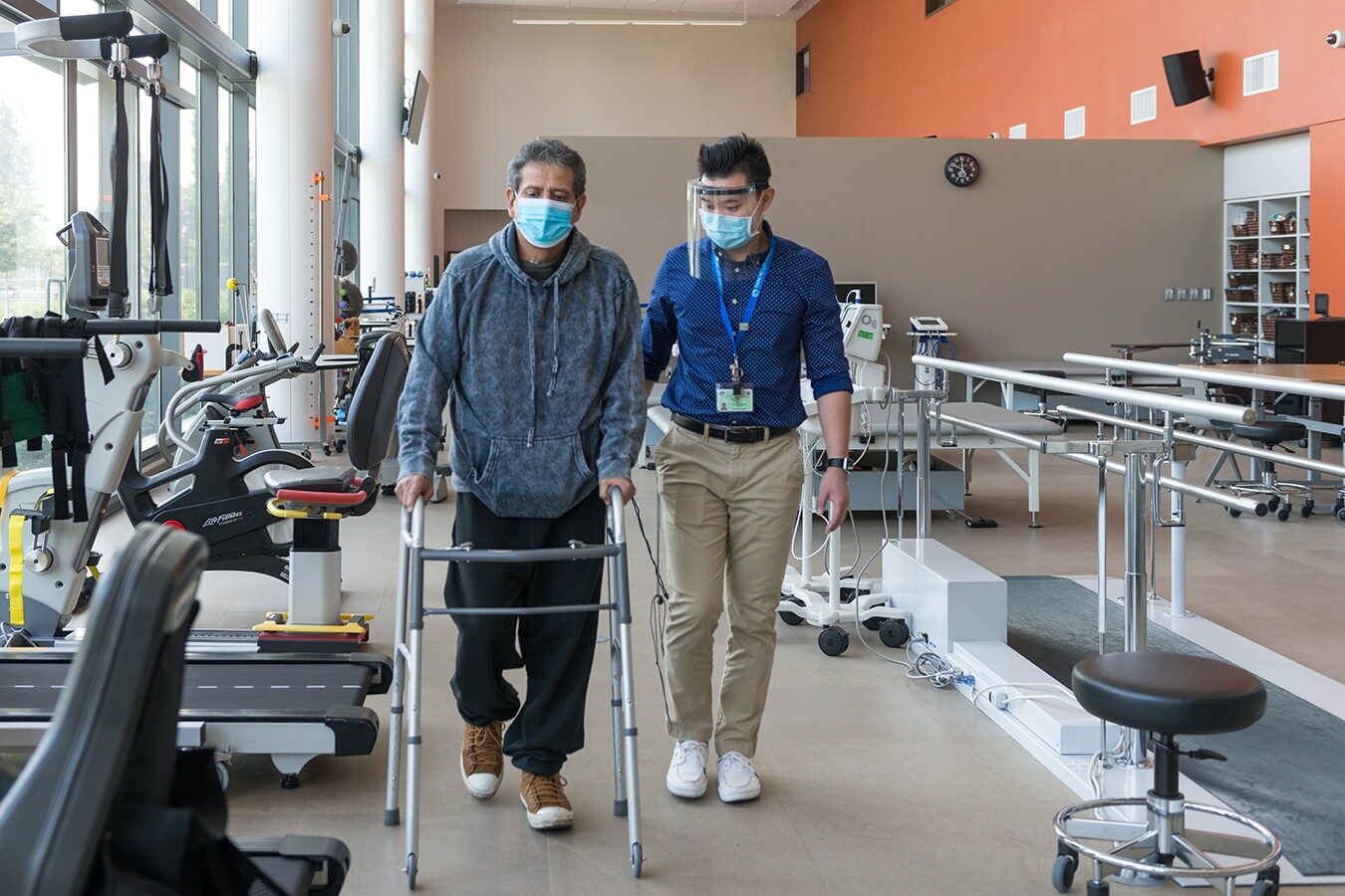 Perez walks around the room while a physical therapist intern times him.