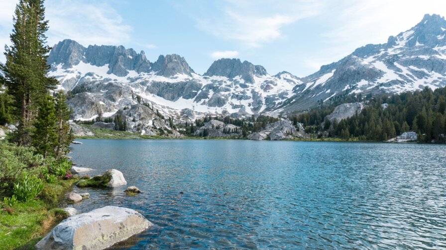 Ediza Lake at Mammoth Lakes is a beautiful clear blue waterscape with snowy mountains.
