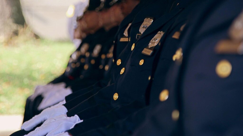 A line of seated policemen's uniforms. | "Frontline: Policing the Police"