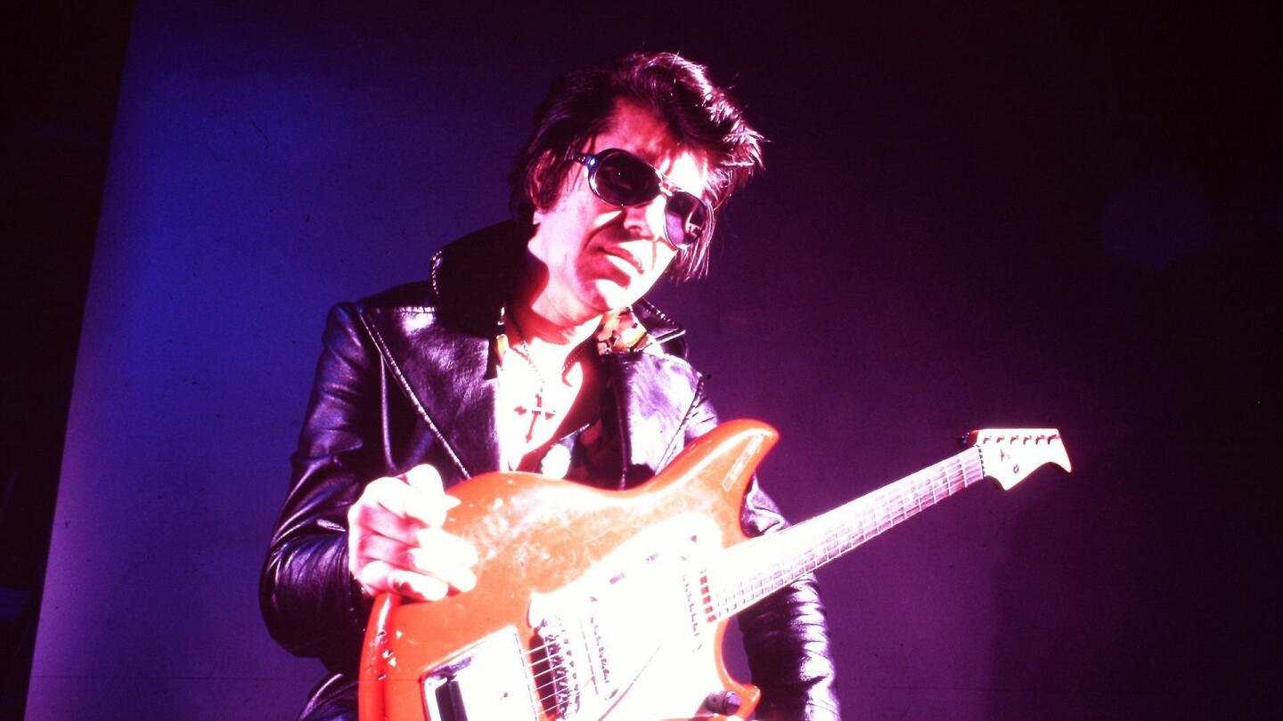 A rock artist poses with his guitar.
