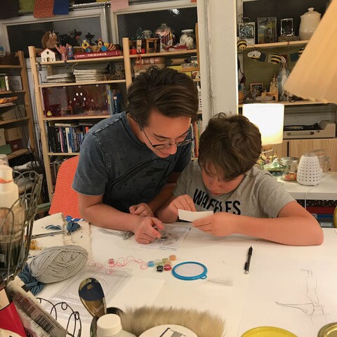 Monica Ramirez Wee's older son goes over the instructions for an arts and craft project with his younger brother.