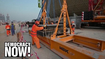 Workers maneuver building materials on machinery.