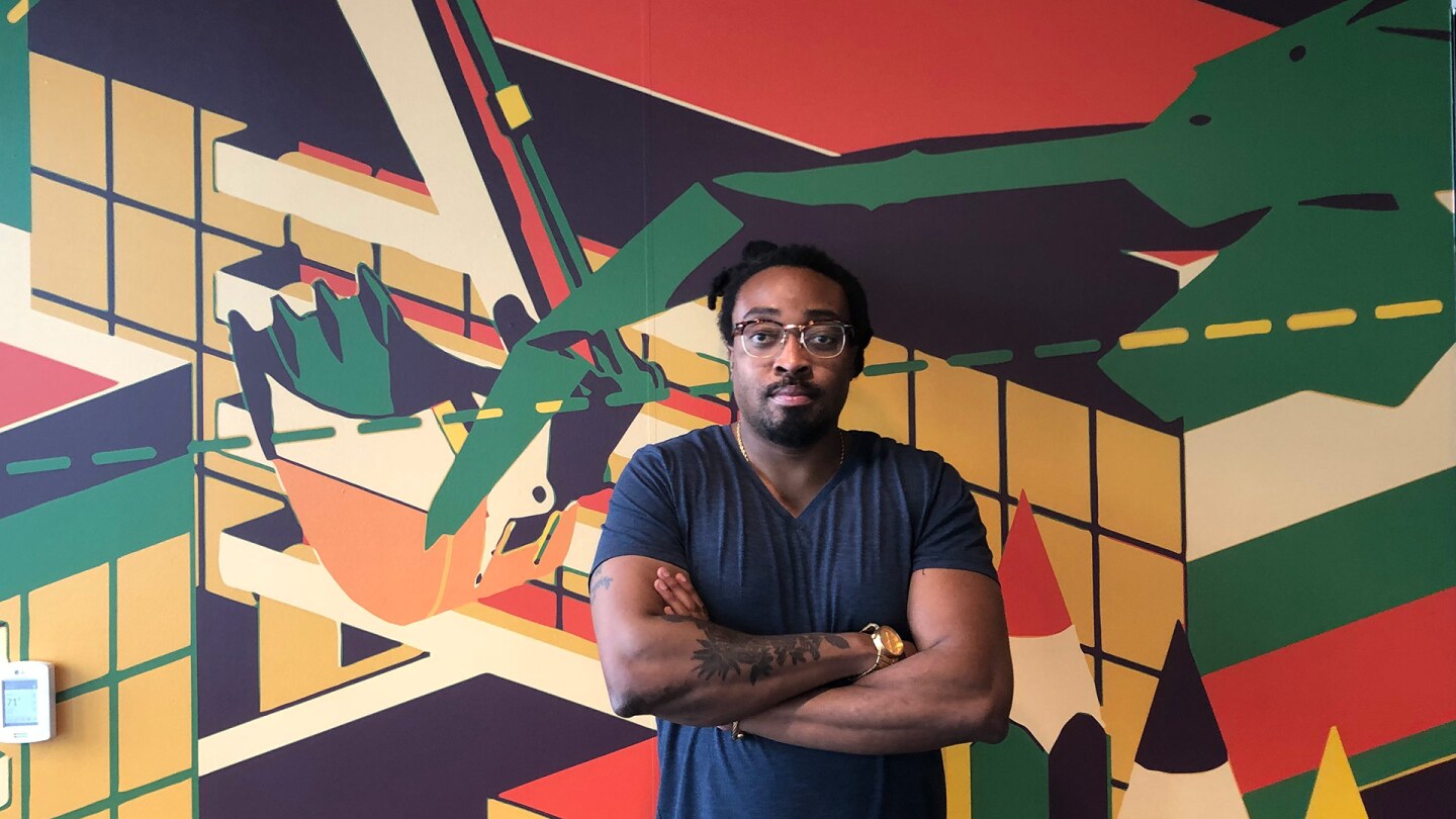 LA County Department of Arts and Culture civic artist Olalekan Jeyifous in front of his artwork, "Extraordinary Experiences in Everyday Places" at the DOORS Re-entry Center.