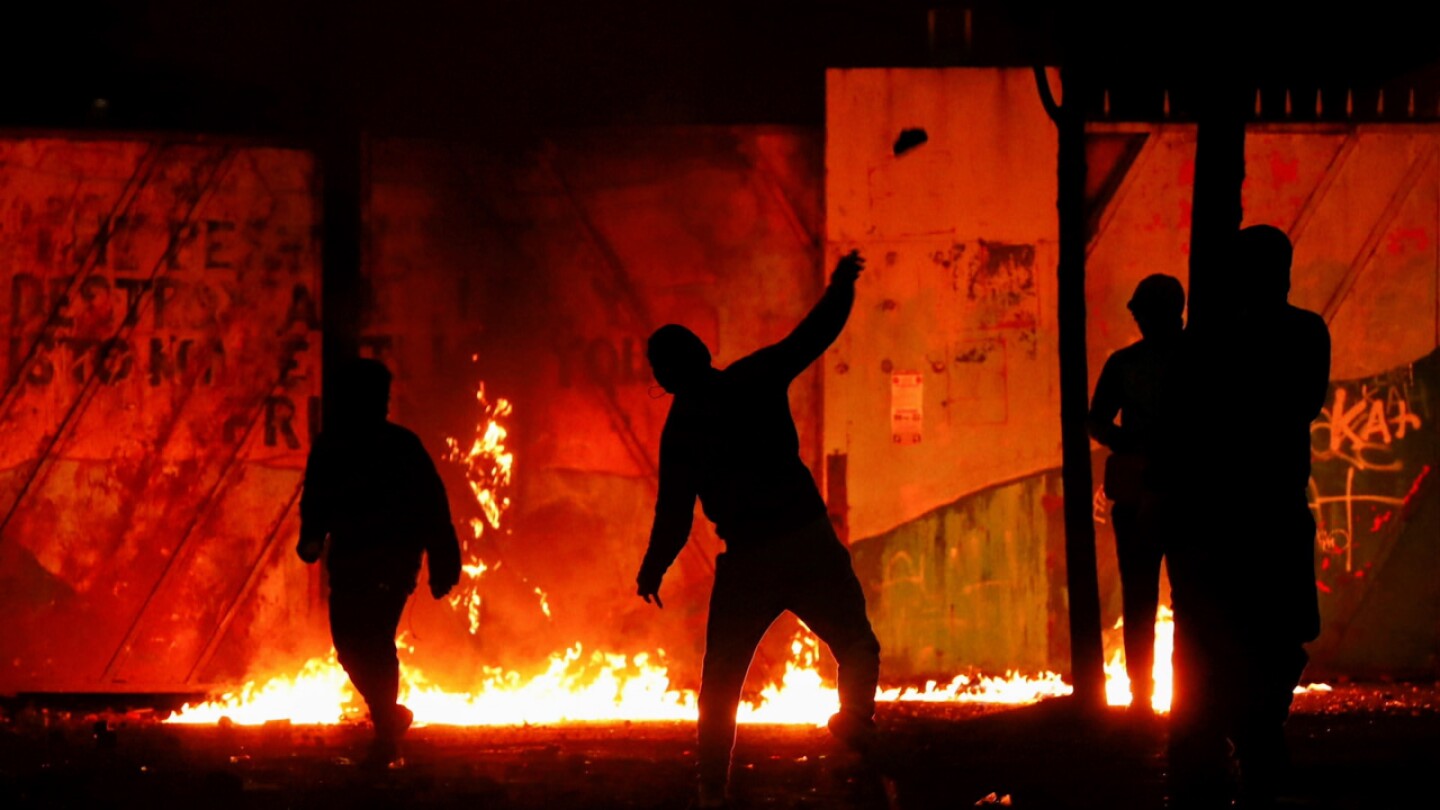 Silhouettes of people vandalizing something set ablaze.