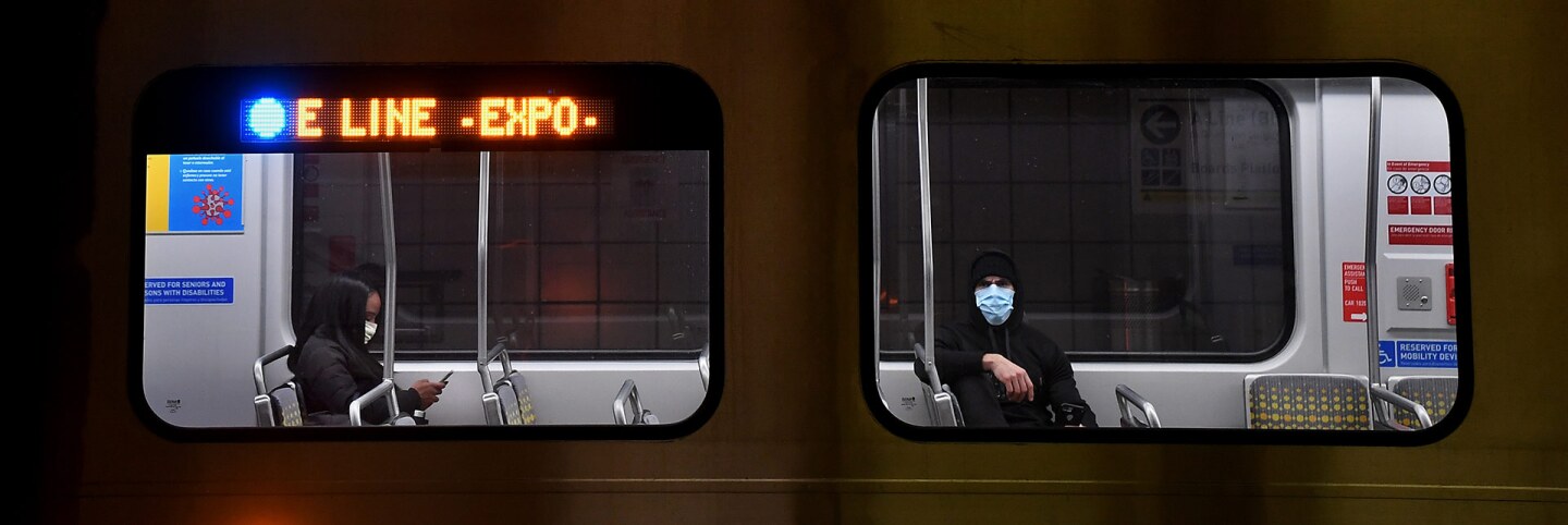 Passengers wear masks during a coronavirus breakout on the Metro train in Downtown Los Angeles. | Wally Skalij/Los Angeles Times via Getty Images