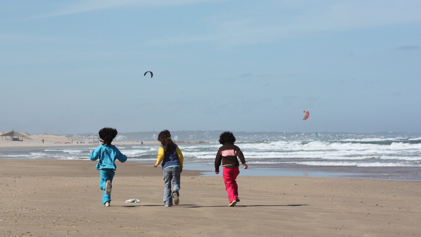 Tres niños corren en una playa