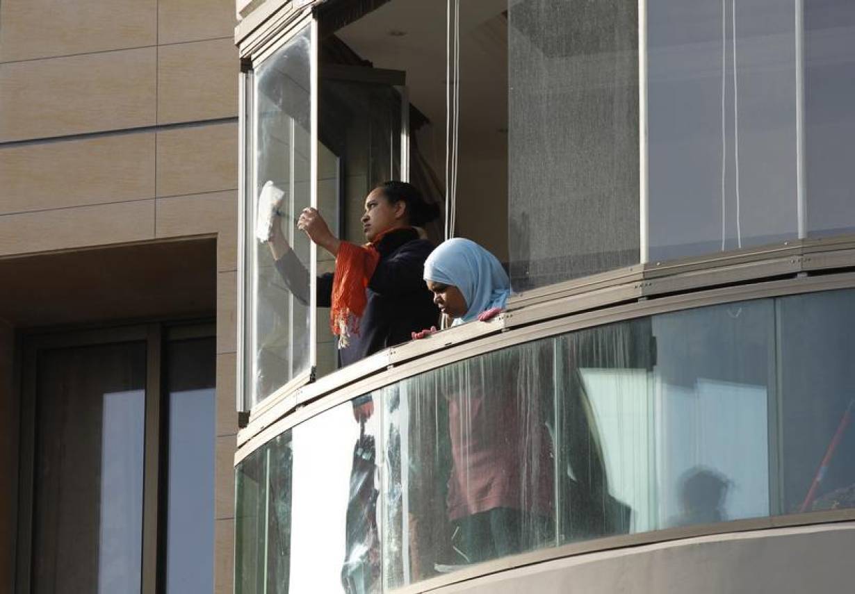Housemaids clean windows in an apartment in Beirut April 2, 2012. Tragic tales of domestic worker abuse in Lebanon are common. | REUTERS/Jamal Saidi