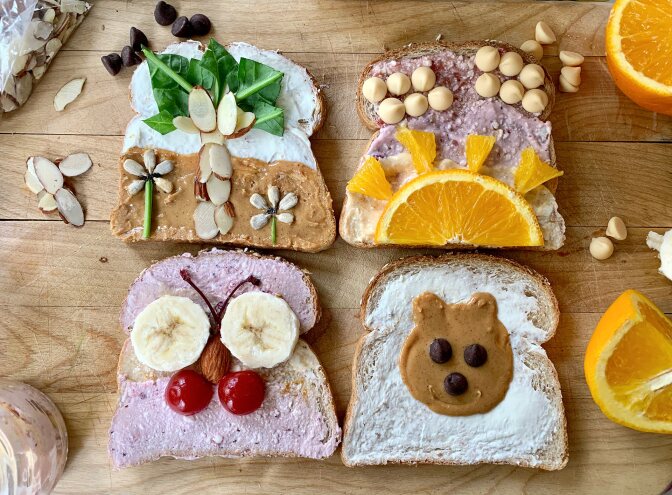 Four pieces of decorated toast featuring a palm tree, sunset, butterfly and teddy bear.