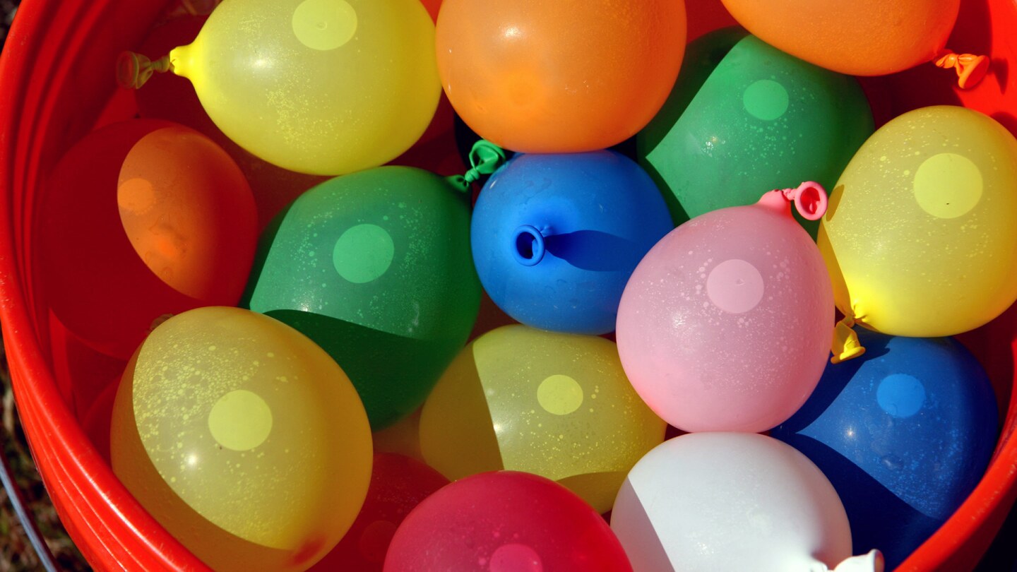 Una canasta llena de globos de agua de muchos colores.