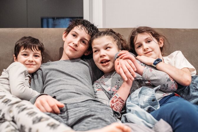 Four children hugging in the sofa