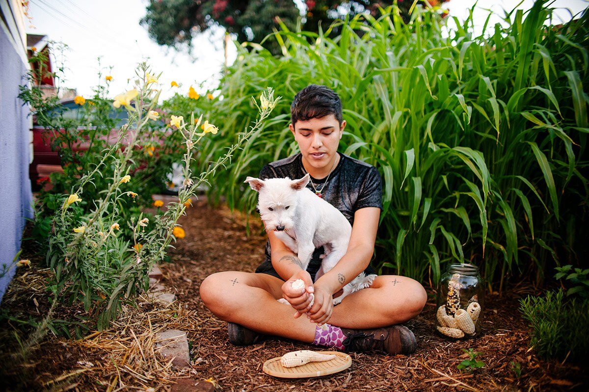 Loba sits in the garden of their East Hollywood home with a white dog. | Samanta Helou Hernandez