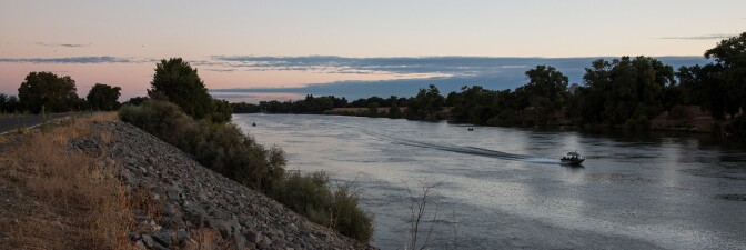 A boat floats down the Sacramento River next to a levee. | Photo by Andrew Burton/For The Washington Post via Getty Images