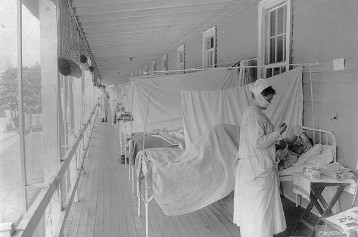 November 1918: A nurse takes a patient's pulse in the influenza ward of Walter Reed Hospital in Washington, D.C. | Harris & Ewing/Library of Congress