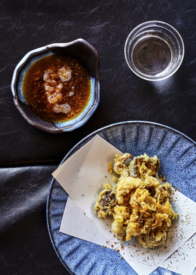 A cup of honjozo with mushroom tempura and dipping sauce.