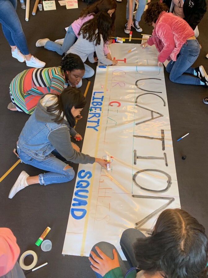 Members of the ACLU Liberty Squad working on a large poster about education.