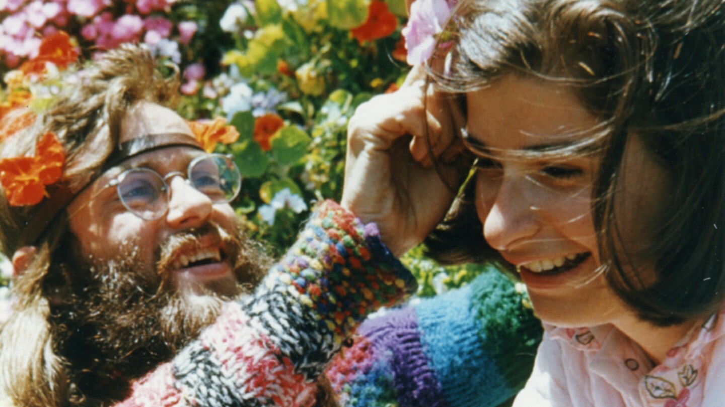 A man places flowers into Penny Cooper's hair. | "Penny: Champion of the Marginalized"