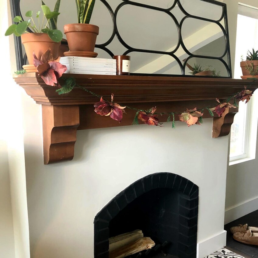 A Thanksgiving fall garland made of leaves hangs on a fireplace.