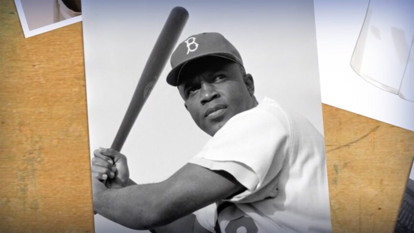 Black and white photo of an African American man in a baseball uniform holding a bat.