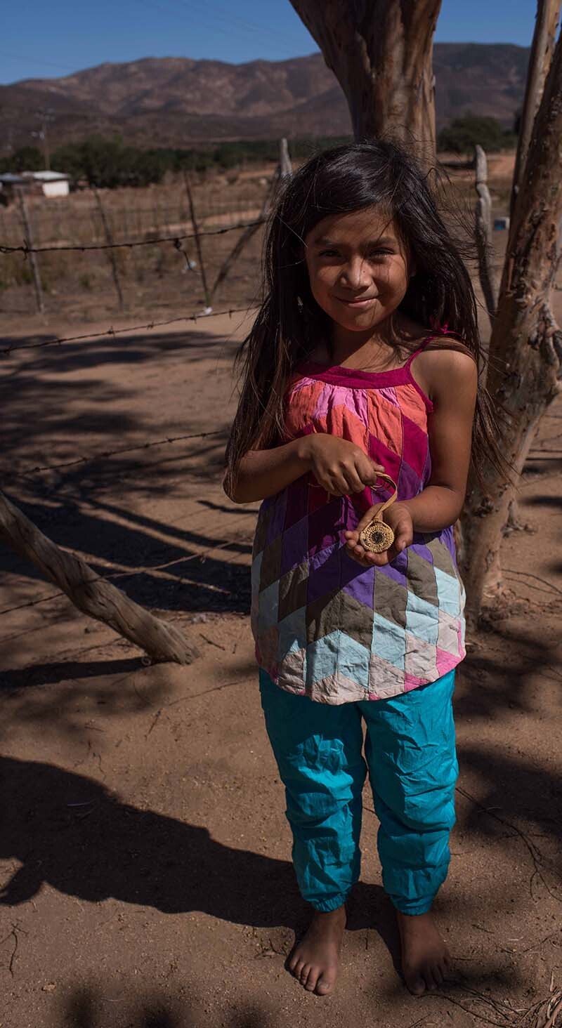 Little girl with a basket necklace she made | Rose Ramirez