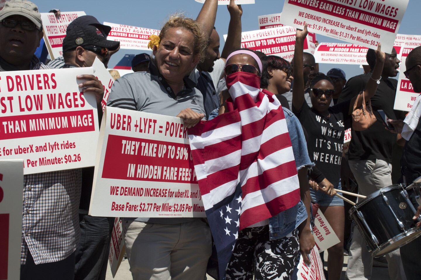 Protesters from Uber and Lyft hold signs demanding higher wages