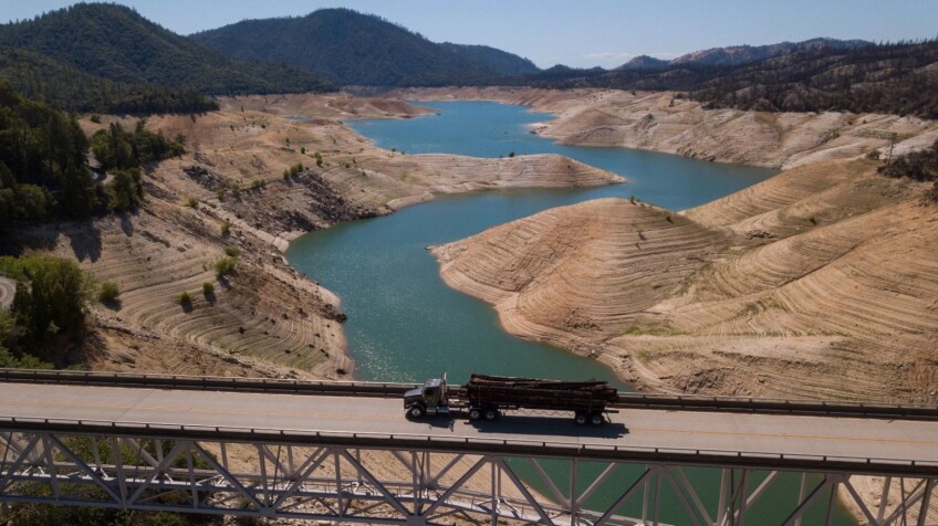 A semi truck crosses a bridge over the drought-stricken Oroville reservoir, whose low water level exposes the higher water lines of years past.