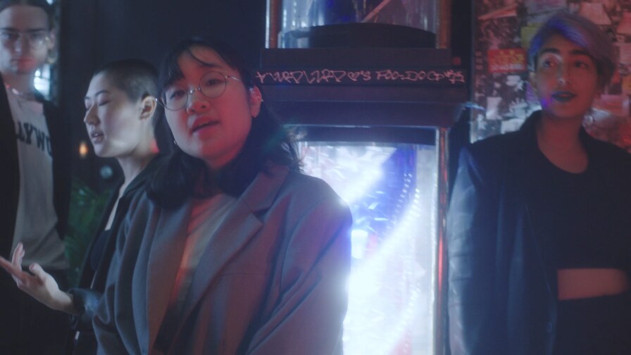 Still from "Drink Im Sippin:" A few people stand looking at the camera, at night.