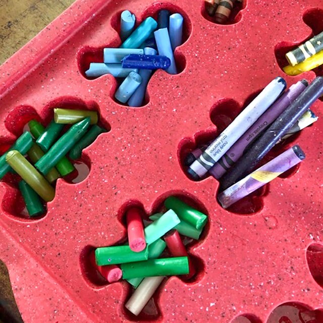 Pieces of crayons in a silicone baking tray with gingerbread doll shapes.