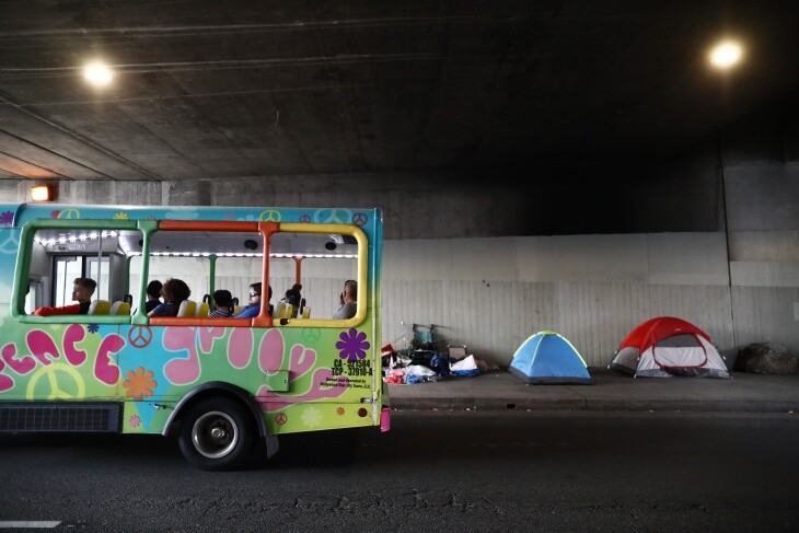 A tour bus passes a homeless encampment located beneath an overpass on June 5, 2019 in Los Angeles. | Mario Tama/Getty Images via LAist