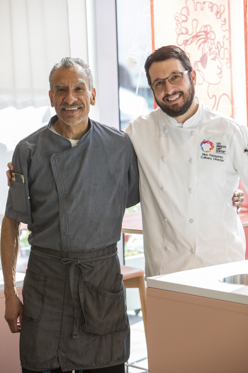 Two men standing side by side. They are wearing culinary clothes.