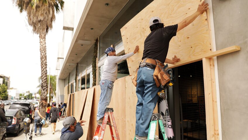Workers board up the Adidas store on Melrose Avenue on Sunday, May 31, 2020. | Christina House / Los Angeles Times via Getty Images