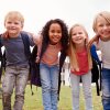 Seven small children of different skin tones huddle together and smile at the camera. iStock