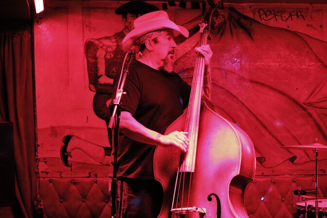 Double bass player with hat under a red light