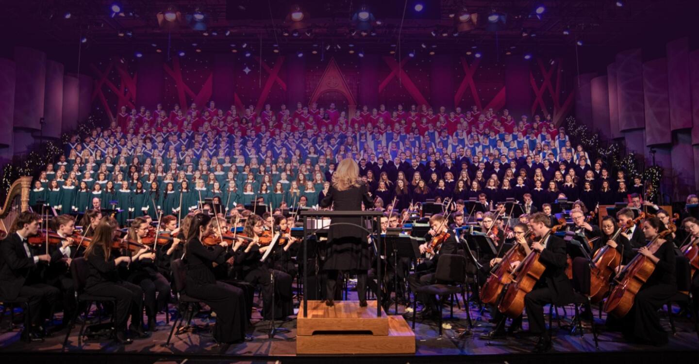 A conductor conducts an orchestra on stage.