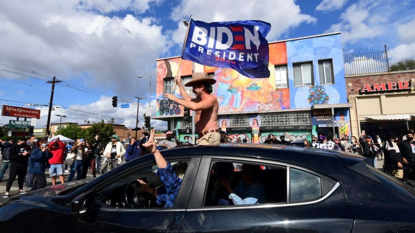 A man waves a Biden flag from his car as people take to the streets in Los Angeles on Nov. 7, 2020 to celebrate Joe Biden and the Democratic Party's victory in the 2020 presidential election. | Frederic J. Brown/AFP via Getty Images
