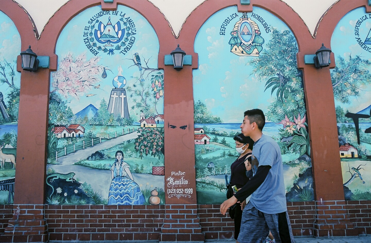 A family walks past a mural of the different Central American countires.